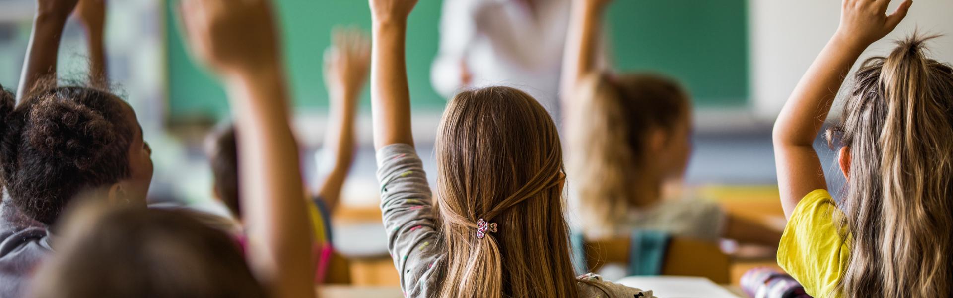 students raising hand in classroom